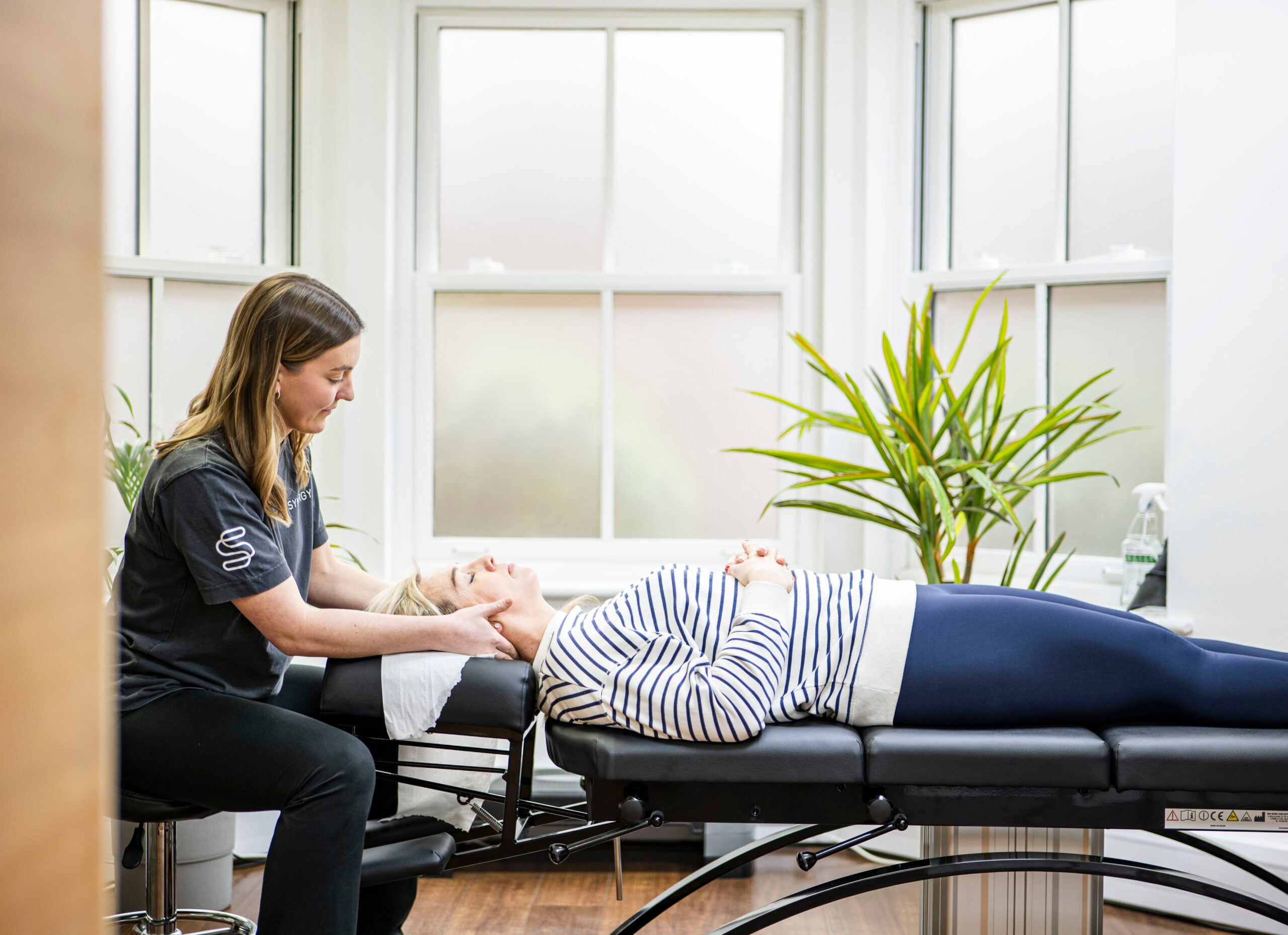 Therapist providing facial treatment to reclining client